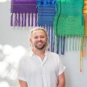 Steven Frost in front of a Pride flag he created that's on display in the CU Art Museum.