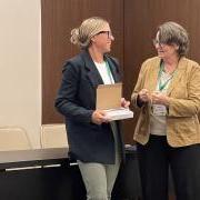 Ashley Carter accepts her best paper award from a woman onstage at the conference.