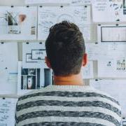 Student staring at a wall full of sticky notes and other pages of work.