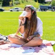 Photo of a student sipping on a coffee and enjoying a sunny day on the Business Field.